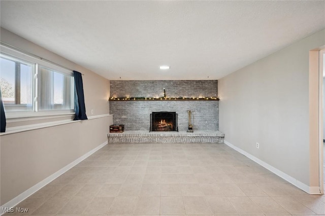 unfurnished living room with baseboards, a brick fireplace, and light tile patterned flooring