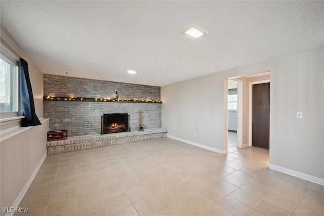 unfurnished living room featuring plenty of natural light, a fireplace, and baseboards