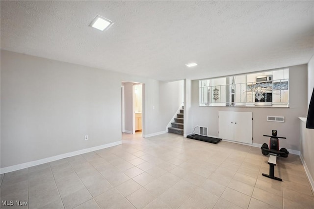 exercise room featuring baseboards, visible vents, and a textured ceiling