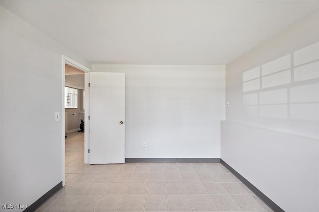 empty room featuring light tile patterned floors and baseboards