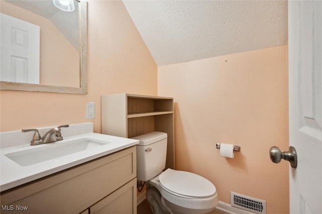 half bathroom with visible vents, toilet, vanity, lofted ceiling, and a textured ceiling