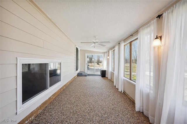 unfurnished sunroom featuring a ceiling fan