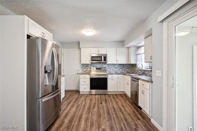 kitchen featuring a sink, decorative backsplash, white cabinetry, and stainless steel appliances