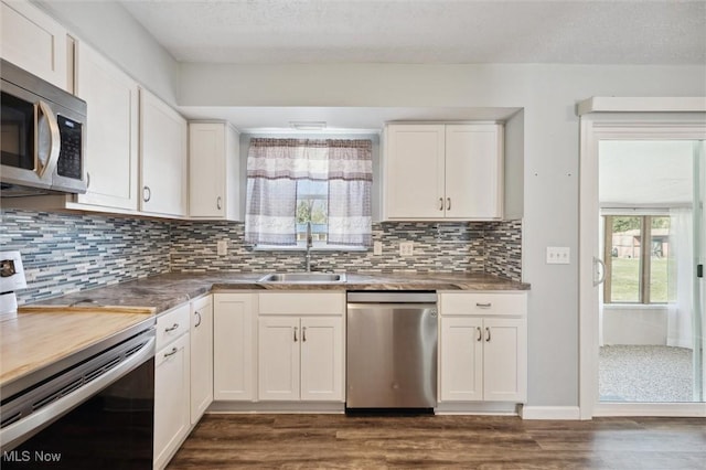 kitchen featuring backsplash, stainless steel appliances, dark wood-style floors, white cabinetry, and a sink