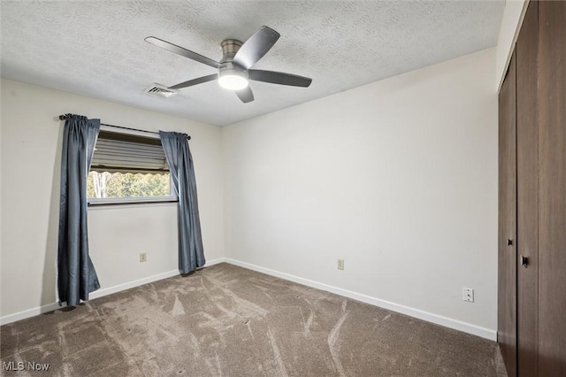 carpeted empty room with visible vents, baseboards, a textured ceiling, and a ceiling fan