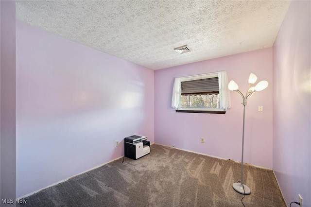 empty room featuring visible vents, carpet floors, and a textured ceiling