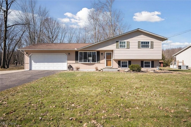 tri-level home with aphalt driveway, a garage, a front yard, and stucco siding