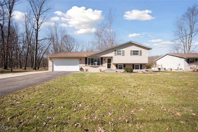 split level home with aphalt driveway, a garage, a front yard, and stucco siding