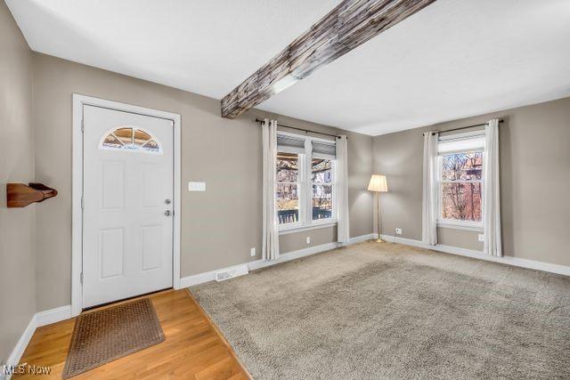 entryway featuring baseboards, beam ceiling, visible vents, and wood finished floors