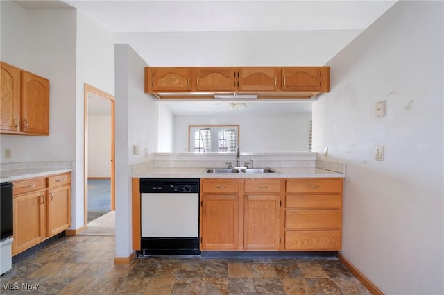 kitchen with a sink, stone finish flooring, light countertops, and white dishwasher