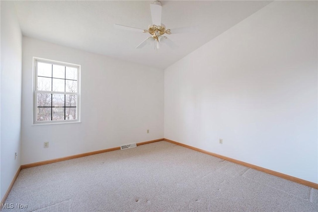 empty room featuring visible vents, lofted ceiling, a ceiling fan, baseboards, and light colored carpet