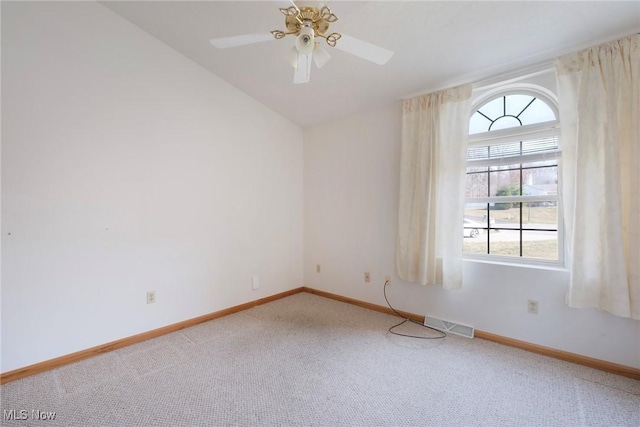 carpeted spare room featuring visible vents, ceiling fan, baseboards, and vaulted ceiling