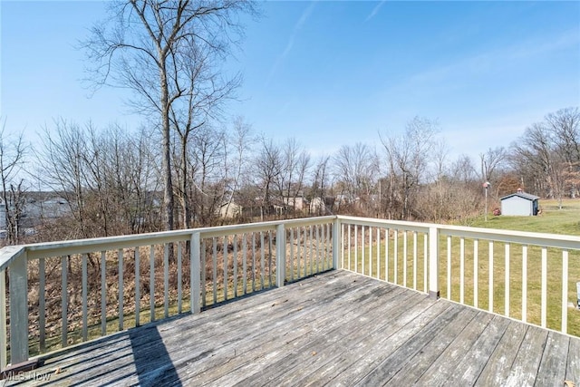 wooden deck featuring an outbuilding, a lawn, and a storage shed