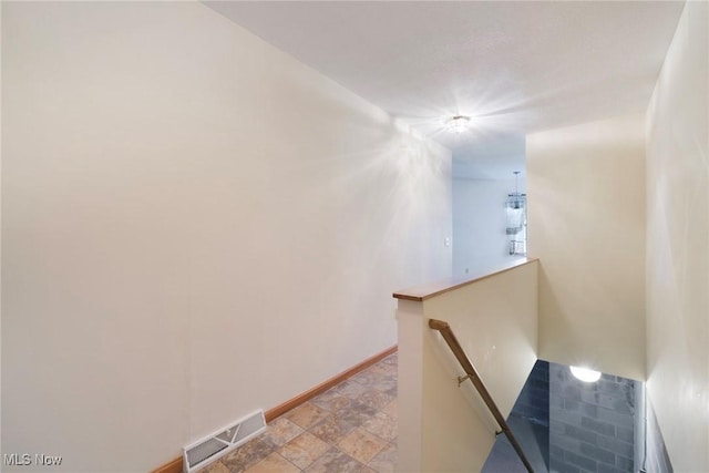 stairway with visible vents, baseboards, and stone finish floor