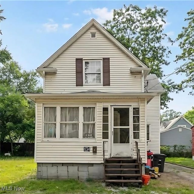 rear view of property with a lawn and entry steps