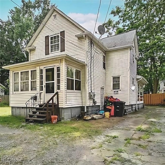 rear view of property with entry steps and fence