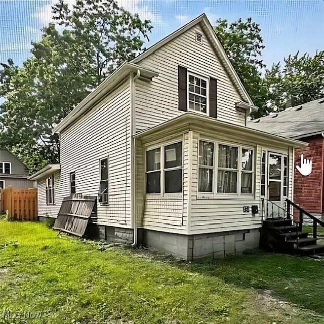 view of side of property featuring a yard, fence, and entry steps