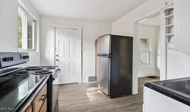 kitchen with visible vents, electric range oven, freestanding refrigerator, wood finished floors, and arched walkways