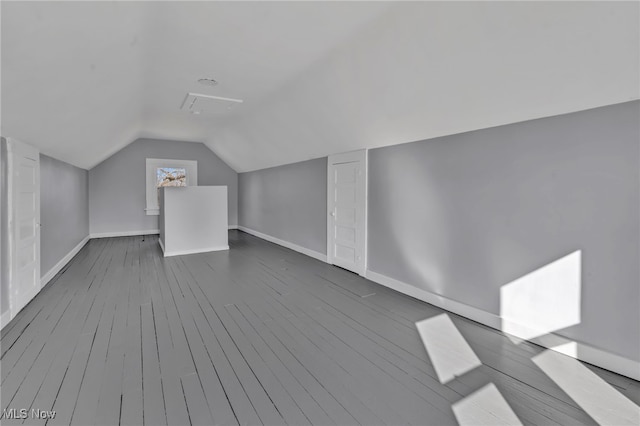 bonus room with dark wood finished floors, lofted ceiling, and baseboards