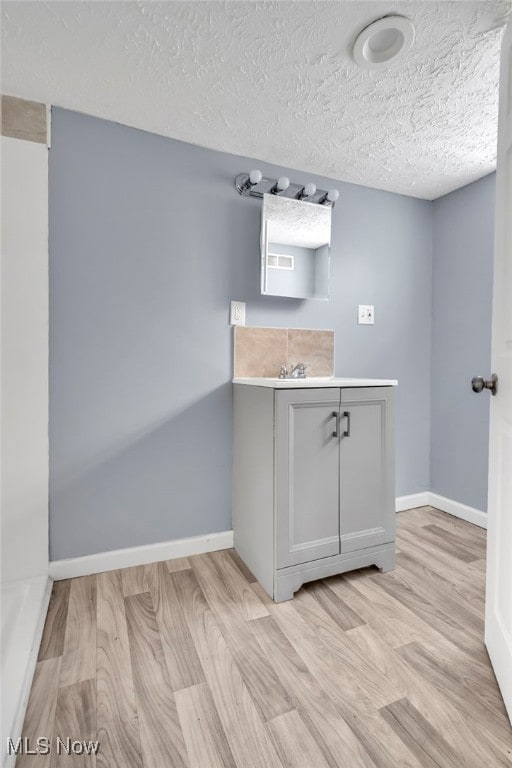 bathroom with visible vents, a textured ceiling, wood finished floors, baseboards, and vanity