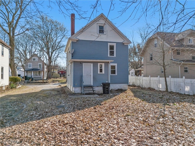 back of property featuring entry steps, fence, and a chimney