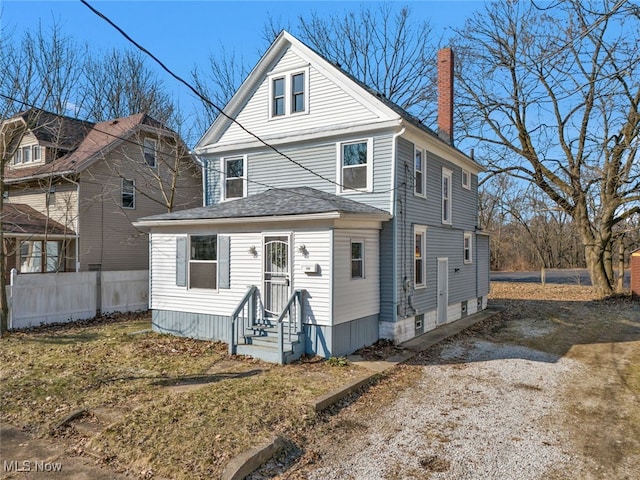 american foursquare style home with fence, entry steps, roof with shingles, a chimney, and driveway