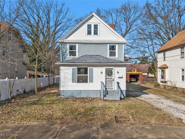 american foursquare style home featuring an outbuilding, a chimney, driveway, and fence