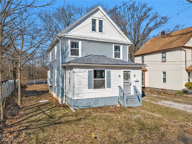 traditional style home featuring entry steps, roof with shingles, a front lawn, and fence