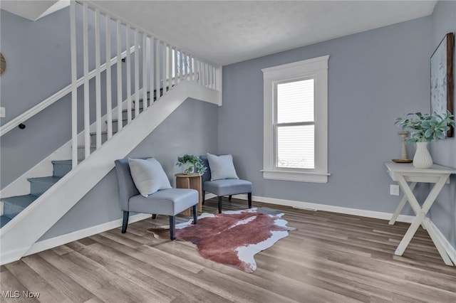 sitting room featuring stairs, baseboards, and wood finished floors