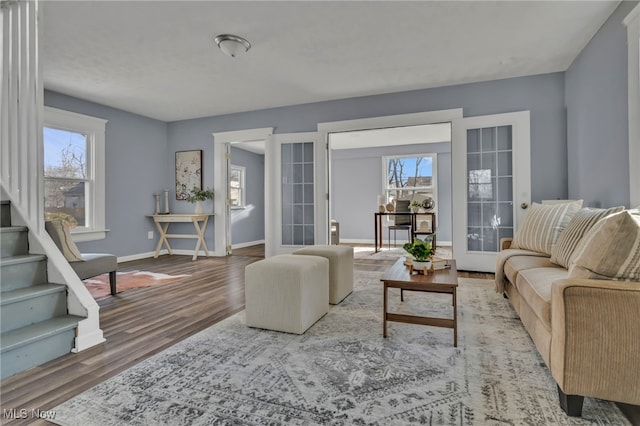 living room with stairs, wood finished floors, baseboards, and french doors