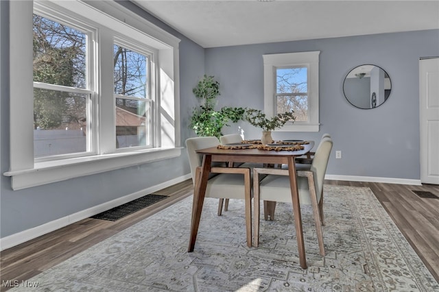 dining area featuring visible vents, baseboards, and wood finished floors