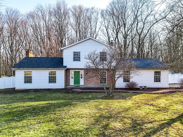 view of front of home featuring brick siding, a chimney, a front lawn, and fence