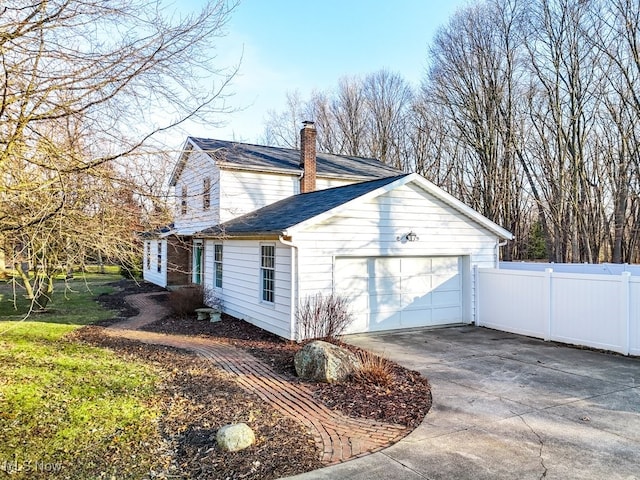 view of property exterior with fence, an attached garage, a shingled roof, a chimney, and concrete driveway