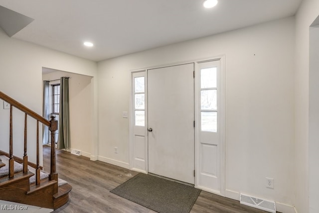 foyer entrance with visible vents, wood finished floors, recessed lighting, stairway, and baseboards