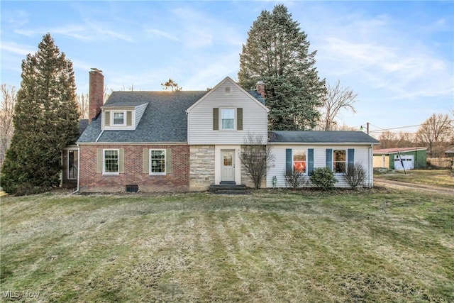 view of front facade featuring brick siding, a chimney, a front yard, and roof with shingles