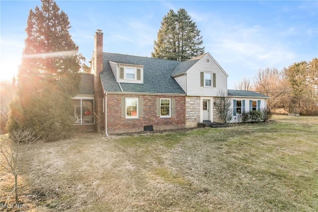 view of front of property featuring brick siding, roof with shingles, a front yard, a chimney, and a sunroom