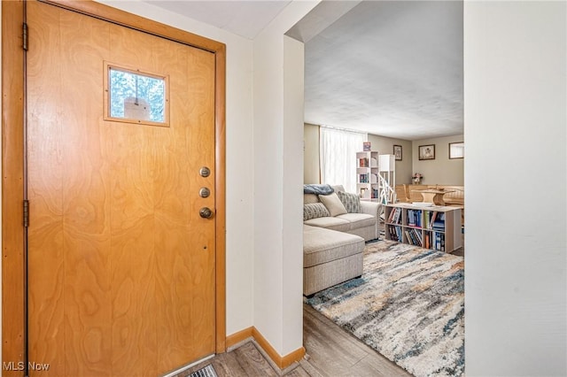 foyer entrance with baseboards and wood finished floors