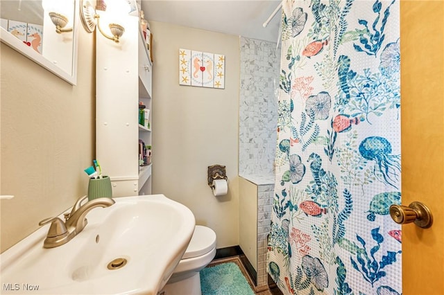 bathroom featuring a sink, curtained shower, and toilet