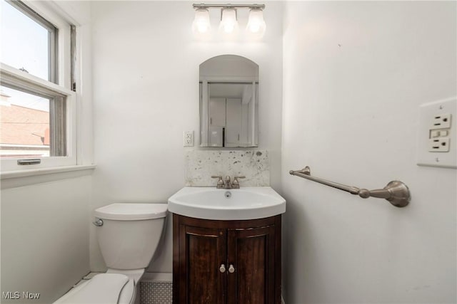 bathroom with decorative backsplash, toilet, and vanity