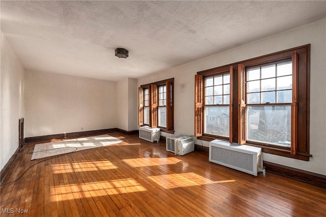 empty room featuring a textured ceiling, baseboards, and hardwood / wood-style floors