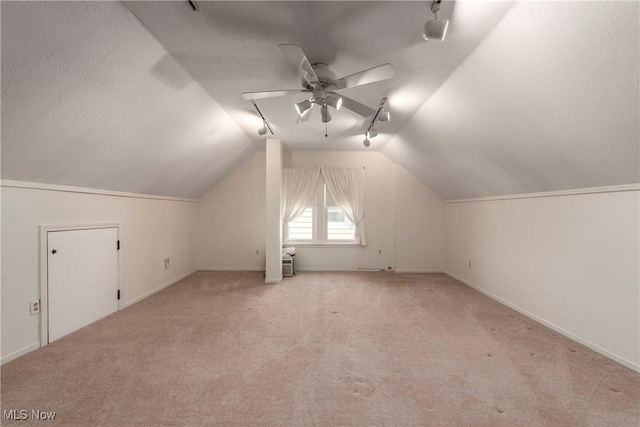 additional living space featuring carpet, baseboards, lofted ceiling, ceiling fan, and a textured ceiling