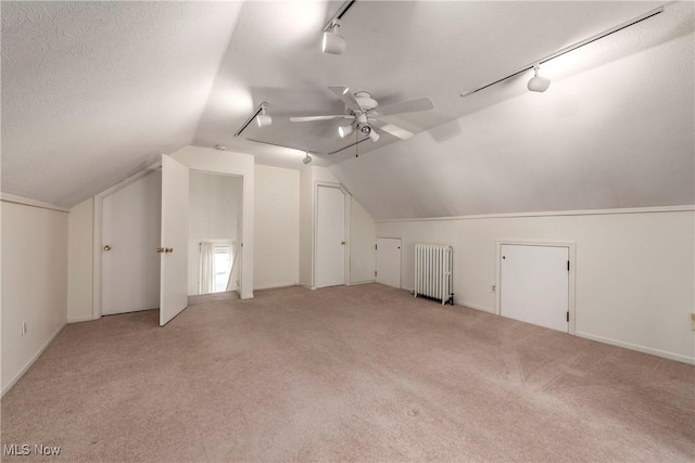 additional living space with radiator, carpet, a ceiling fan, vaulted ceiling, and a textured ceiling