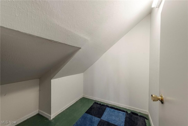 bonus room with vaulted ceiling, baseboards, and a textured ceiling