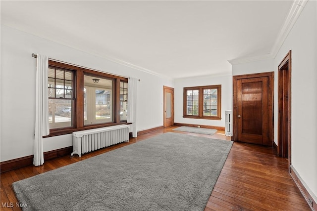 interior space with baseboards, crown molding, radiator heating unit, and hardwood / wood-style flooring