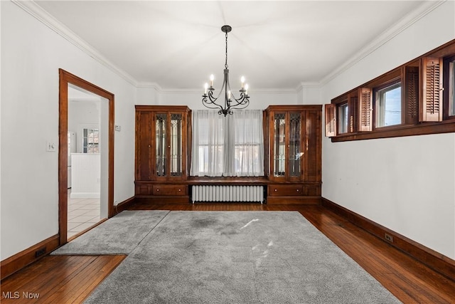 unfurnished room featuring a chandelier, crown molding, radiator heating unit, and wood-type flooring