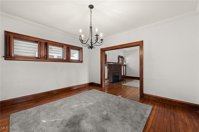 empty room with ornamental molding, dark wood-style floors, baseboards, and a chandelier