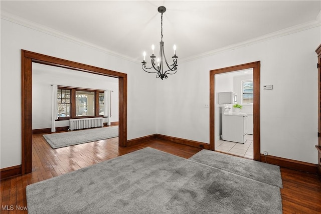 unfurnished dining area with hardwood / wood-style floors, a notable chandelier, radiator, and washer / dryer