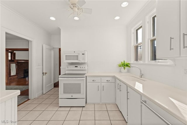 kitchen with a sink, white appliances, light tile patterned flooring, crown molding, and light countertops