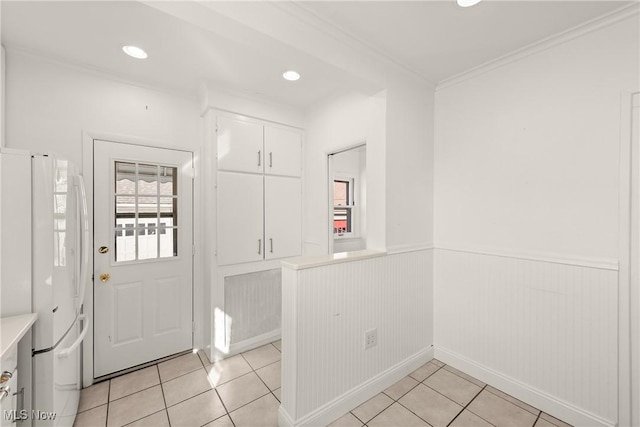 foyer entrance with light tile patterned floors, a wainscoted wall, ornamental molding, and recessed lighting