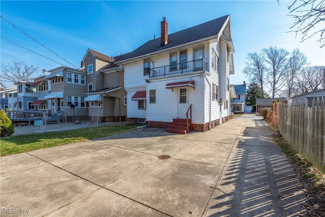 back of house featuring a residential view, fence, a chimney, and entry steps